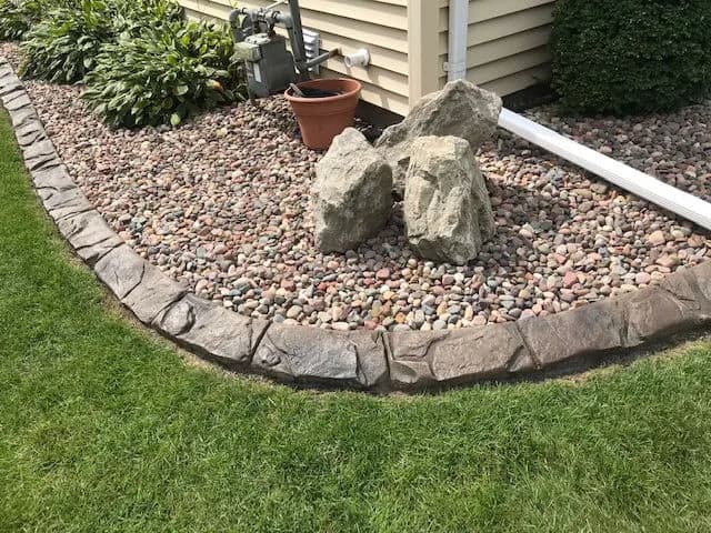 Landscape design featuring decorative rocks and pebbles in a garden border.